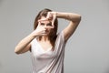 Closeup of young beautiful brunette woman making frame with her fingers, over gray background Royalty Free Stock Photo