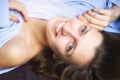 Closeup of young beautiful smiling woman in blue lying in bed. Natural beauty. Royalty Free Stock Photo