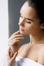 Closeup of a young beautiful woman with nude makeup touching her face. Beauty, spa. Holding Moisturizing Lotion. Skin Care Concept Royalty Free Stock Photo