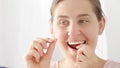 Closeup of young brunette woman taking care of her teeth and using dental floss. Concept of teeth health, self checking mouth and Royalty Free Stock Photo