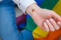 Closeup of young caucasian millennial hippie woman with a rainbow flag in heart shape painted in wrist. Rainbow color