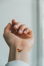 Closeup of young caucasian millennial hippie woman with a rainbow flag in heart shape painted in wrist. Rainbow color