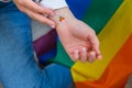 Closeup of young caucasian millennial hippie woman with a rainbow flag in heart shape painted in wrist. Rainbow color