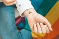 Closeup of young caucasian millennial hippie woman with a rainbow flag in heart shape painted in wrist. Rainbow color