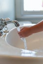 Closeup of young child washing hands under running water at the