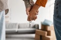 Closeup of young couple holding hands and new house key, moving in together. Mortgage, real estate concept Royalty Free Stock Photo