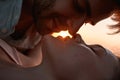 Closeup of young couple in love kissing on sunset while relaxing together on the beach Royalty Free Stock Photo