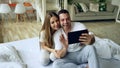 Closeup of Young cute and loving couple having video chat holding smartphone and chatting to friends sitting in bed at Royalty Free Stock Photo