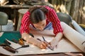 Closeup young female leather goods maker is drawing a design on leather in leather workshop