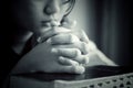 Closeup  Of Young Girl In Silence Prayer Pose. With Clenched Hands On A Bible Book, Praying After Reading The Bible In Black And