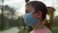 Young guy standing in medical mask outdoors. Teen boy caring from coronavirus. Royalty Free Stock Photo