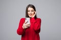 Closeup of young happy woman wearing in red sweater with mobile phone, over white background Royalty Free Stock Photo