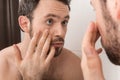 Closeup of young man examining his eye in mirror. Royalty Free Stock Photo