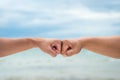 Closeup young man fist bump on the blue sky sea background. Friendship & Teamwork Concept. Royalty Free Stock Photo