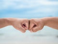 Closeup young man fist bump on the blue sky sea background. Friendship & Teamwork Concept. Royalty Free Stock Photo