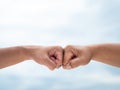 Closeup young man fist bump on the blue sky sea background. Friendship & Teamwork Concept. Royalty Free Stock Photo