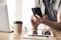 Closeup of young man hands with smart phone and laptop at home. Businessman working on computer in office Royalty Free Stock Photo