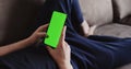 Closeup young man lying on a couch and using smartphone with green screen Royalty Free Stock Photo