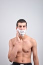 Closeup of young man preparing to shave, he puts foam on his c