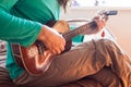 Closeup of a young man`s hands playing an acoustic guitar ukulele at the home. Man holding ukulele. Royalty Free Stock Photo