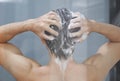 Closeup young man washing hair with with shampoo in the bathroom, vintage tone, selective focus Royalty Free Stock Photo