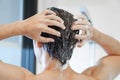 Closeup young man washing hair with with shampoo in the bathroom, vintage tone, selective focus Royalty Free Stock Photo