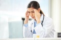 Closeup of a young mixed race doctor looking worried and suffering from a headache while working on a computer in her Royalty Free Stock Photo