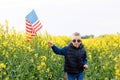 Boy standing with the american flag on the green and yellow field celebrating national independence day. 4th of July concept Royalty Free Stock Photo