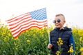 Boy standing with the american flag on the green and yellow field celebrating national independence day. 4th of July concept Royalty Free Stock Photo