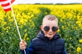 Boy standing with the american flag on the green and yellow field celebrating national independence day. 4th of July concept Royalty Free Stock Photo