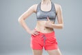 Closeup of young slim woman show thumbs up with six-pack torso on white background