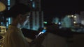 Closeup of young smiling woman texting on smartphone standing on rooftop terrace at night Royalty Free Stock Photo