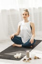 Closeup young sporty fit girl doing hatha yoga on a modern Yoga studio. She sits on the lotus position and meditate Royalty Free Stock Photo