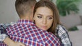 Closeup of young upset couple embrace each other after quarrel. Woman looking wistful and sad hug her boyfrined at home