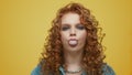 Woman chewing gum in studio. Girl blowing bubble gum on yellow background Royalty Free Stock Photo