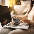 In a closeup, a young woman is engrossed in online shopping on her laptop, credit card in hand, as she explores the enticing world