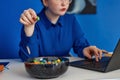 Closeup of young woman enjoying candy snack while using laptop in vibrant office