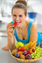 Closeup on young woman with fruits plate eating strawberry