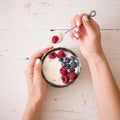 Closeup of Young woman hands with a bowl of yogurt. Girl eating organic yogurt for breakfast with fresh berries