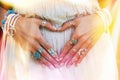 Closeup of young woman hands in heart shape with lot of boho sty