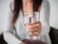 Closeup young woman holding drinking water glass in her hand Royalty Free Stock Photo
