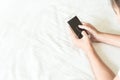Closeup young woman holding smart phone lying on bed, happy and Royalty Free Stock Photo