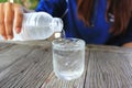 Closeup of young woman pouring water from a plastic bottle into glass on table in restaurant Royalty Free Stock Photo