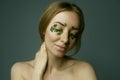 Closeup of young woman`s face with boxwood leaf patches.