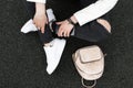 Closeup of a young woman`s legs in ripped fashionable black jeans in leather stylish with sneakers with snake pattern