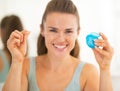 Closeup on young woman showing dental floss