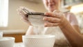 Closeup of young woman sifting flour through metal sieve on domestic kitchen Royalty Free Stock Photo