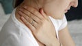 Closeup of young woman sitting on bed and rubbing her aching neck in morning. Concept of healthcare problems, pain relief and Royalty Free Stock Photo