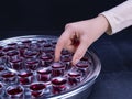 Closeup of young woman taking communion from small cups on black background