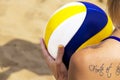 CLOSEUP A young woman with a tattoo on her back prepares to play. Athletic girl playing beach volleyball during her fun summer